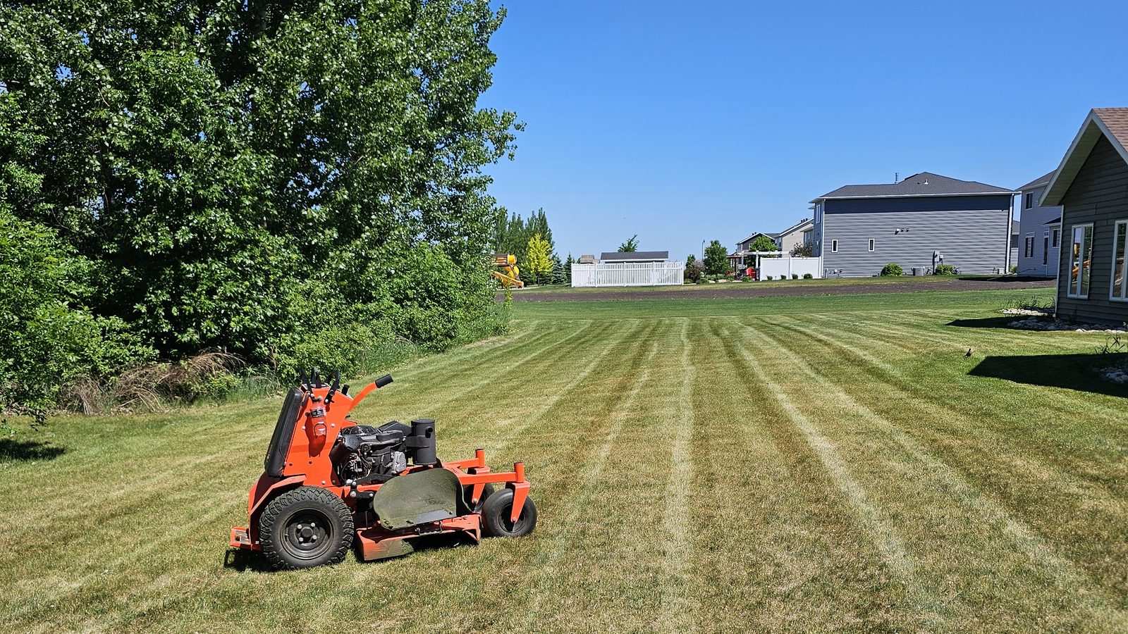 Striped lawn freshly cut with stand-on mower